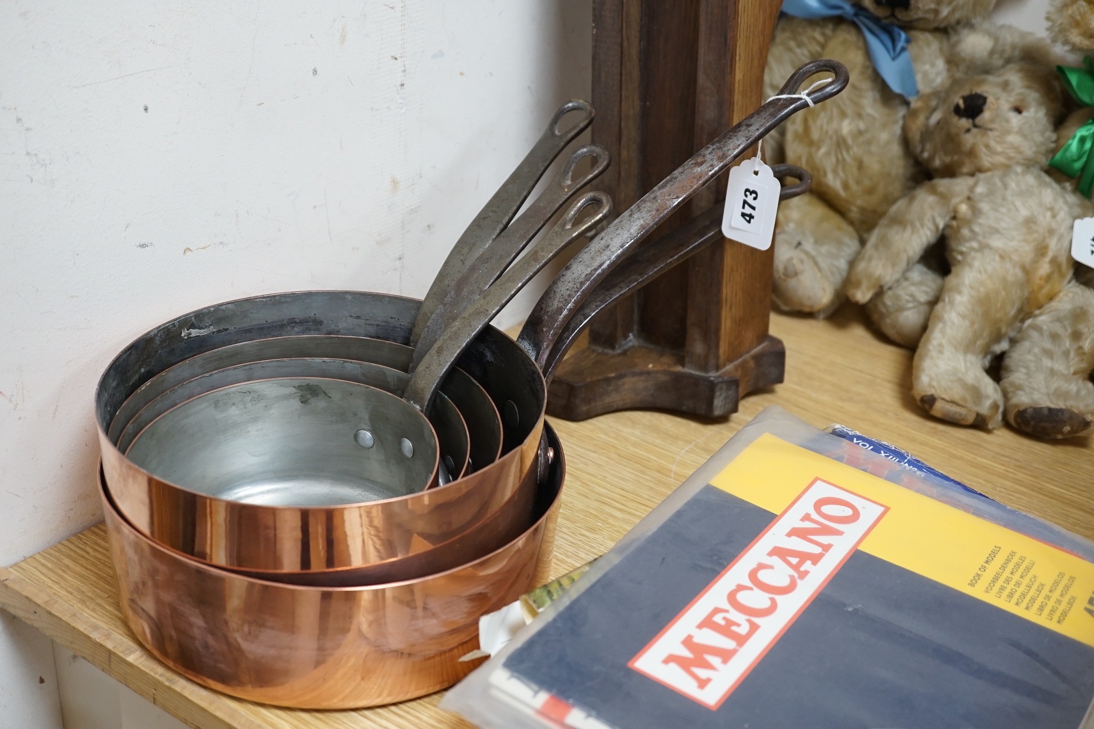 A matching set of five graduating copper pans and an oak pan rack